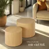 Two round wooden side tables in a living room setting with a sofa and plants. Náhled obrázku produktu
