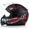A black motorcycle helmet with a red and white graphic design of a monster's face, including teeth and an eye. The helmet has a clear visor. Produktbild-Vorschau