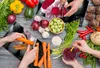 A top-down view of hands preparing vegetables on a wooden table. Náhled obrázku produktu