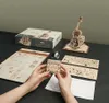 A wooden 3D puzzle of a cello and its components are laid out on a dark surface. Voir les images du produit