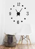 A wall clock with numbers and hands is shown on a white wall, next to a white chair and a woven basket with a gray towel inside. Náhled obrázku produktu