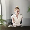 A woman is working on a laptop at a desk in an office. Produktbild-Vorschau