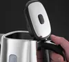 Close-up of a hand holding the handle of a stainless steel kettle with the lid open. Produktbild-Vorschau