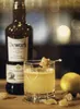 A bottle of Dewar's 12 Year Old Scotch Whisky next to a cocktail, a lemon, and rock candy. Produktbild-Vorschau