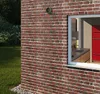Exterior view of a brick building with a window revealing a kitchen interior. Anteprima dell’immagine prodotto