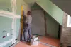 A person is using a level tool to check a wall during construction or renovation. Náhľad obrázku produktu