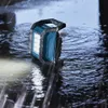 A blue and gray Bosch work light is placed in shallow water with rain falling. Voir les images du produit