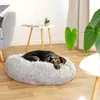 A dog is resting on a plush dog bed next to a small table and a plant. Anteprima dell’immagine prodotto
