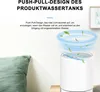 A white dehumidifier with blue swirling air and green leaves depicted above it, suggesting air circulation and purification. A green pillow is visible on the left. Produktbild-Vorschau