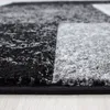 A close-up, low-angle shot of a rug with a geometric pattern in black and gray. Podgląd zdjęcia produktu