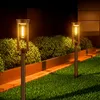 Two solar-powered garden lights illuminate a lawn and garden at night. Anteprima dell’immagine prodotto