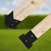 Two wooden beams with black metal brackets attached, set against a blurred background of green grass and a light blue sky. Anteprima dell’immagine prodotto