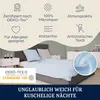A bed with light blue bedding and pillows, with marketing icons and text overlayed on a cream background. Produktbild-Vorschau
