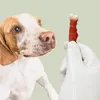 A dog is looking at a treat held by a gloved hand. Anteprima dell’immagine prodotto