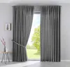 A pair of gray curtains are shown, one partially drawn back, revealing a view of trees and sky outside a window.
