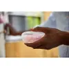A person is holding a clear plastic case with pink pacifiers inside. Anteprima dell’immagine prodotto