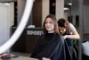 A woman is getting her hair cut by a hairdresser in a salon. Podgląd zdjęcia produktu