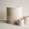 Three cream-colored textured planters of varying sizes are arranged on a light gray surface against a cream-colored background. Produktbild-Vorschau