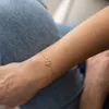 Nahaufnahme eines Frauengelenks mit Fokus auf rose goldene Armkette mit Lebensbaum Anhänger. Produktbild-Vorschau