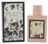 Rechteckiger, rosafarbener Gucci-Flakon mit floral bedruckter Etikette neben schwarzer, geblümter Verpackung in Vintage-Optik. Náhled obrázku produktu
