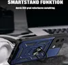 A close-up of a blue and black phone case with a ring stand, placed on a textured surface with a blurred background of a laptop and car. Produktbild-Vorschau