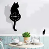 A cat-shaped wall clock is displayed on a wall above a table set for coffee. Produktbild-Vorschau