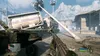 A first-person perspective of a video game scene, showing a weapon and a destroyed environment with industrial elements and mountains in the background. Produktbild-Vorschau