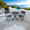A patio set with two chairs and a table is placed on a tiled patio overlooking the sea. Voir les images du produit