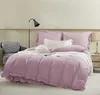 A neatly made bed with pink bedding and pillows, a chair, and a lamp. Podgląd zdjęcia produktu