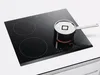 A black induction hob with a small pot on it. Voir les images du produit
