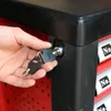 A hand is inserting a key into a lock on a black toolbox. Produktbild-Vorschau