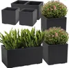 A collection of dark gray square and rectangular planters, some containing green plants and pink flowers, arranged on a white background. Náhled obrázku produktu
