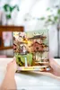 Hands holding a 3D wooden model of a Japanese-style building with cherry blossoms. Náhled obrázku produktu