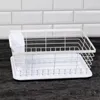 A white dish drying rack sits on a dark countertop with a white tiled wall in the background. Náhled obrázku produktu