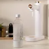 A sparkling water maker and a bottle of sparkling water on a countertop. Produktbild-Vorschau