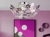 A decorative ceiling lamp with floral elements hangs above a framed artwork on a purple wall. Náhled obrázku produktu