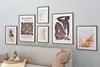 A collection of framed art prints displayed on a wall above a sofa. Produktbild-Vorschau