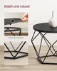 A collage of images showing a black coffee table with a geometric base, highlighting its stability and secure tabletop. A white vase is placed on the table in the main image. Podgląd zdjęcia produktu
