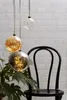 Three decorative glass spheres with LED lights hanging in front of a brick wall, next to a plant and a chair. Produktbild-Vorschau