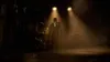 A lone figure in a futuristic suit stands in a dimly lit, smoky environment, illuminated by spotlights. Produktbild-Vorschau