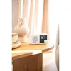 A white Blaupunkt portable radio sits on a wooden table next to a decorative vase and a candle. Náhled obrázku produktu