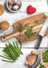 A collection of kitchen items including a cutting board, knife, herbs, garlic, green beans, and a heart-shaped object, arranged on a white wooden surface. Anteprima dell’immagine prodotto