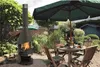 A garden scene with a fireplace, table, and chairs. Produktbild-Vorschau