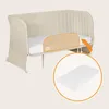 A baby crib with a safety barrier and a mattress shown in a separate circle. Produktbild-Vorschau