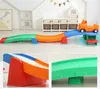 A children's toy car track with multiple sections and a toy car on it, shown in a room with storage units and decorations. Voir les images du produit