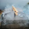Smoke rising from a stainless steel grill with wooden tongs on top. Produktbild-Vorschau