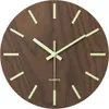 A close-up shot of a wooden wall clock with luminous hour markers and hands. Produktbild-Vorschau