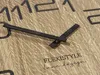 A close-up view of a wooden clock face with black hour markers and hands. The brand name and a slogan are visible on the clock face. Produktbild-Vorschau