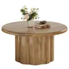 A round wooden coffee table with a fluted drum base, decorated with a vase of flowers and two books. Produktbild-Vorschau