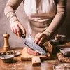 A person is preparing food, specifically cutting meat on a wooden board. Podgląd zdjęcia produktu